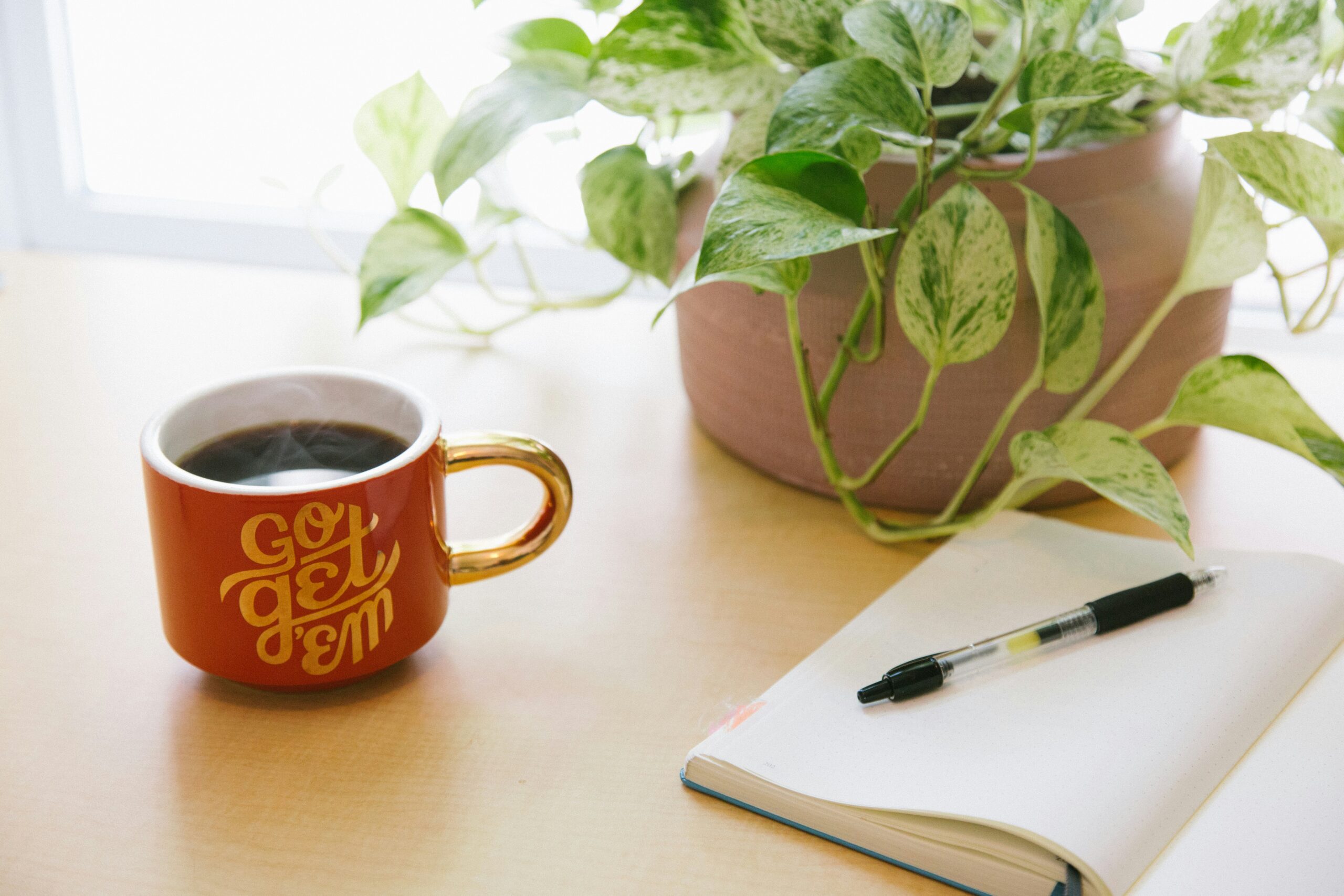 Go get 'em' motivational mug on a desk with journal and plant, perfect inspiration for stay at home moms starting side hustles